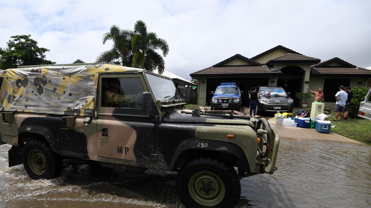 An army vehicle drives past houses affected by floods in Townsville, in 201 after days of torrential rain. Picture: AAP Image/Dan Peled.