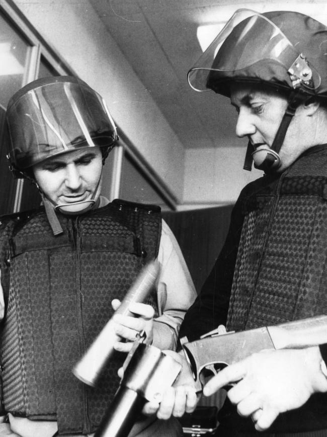 1970: South Australian detectives John Ramsden and Len Oliver try on new fibreglass helmets and bulletproof vests, while holding a tear gas gun and shell. File picture