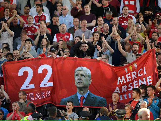 Fans hold up signs celebrating Arsene Wenger.