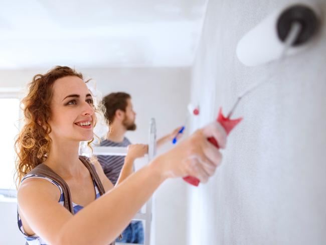 Beautiful young couple having fun and painting walls using paint rollers in their new house. Home makeover and renovation concept. - iSTOCK