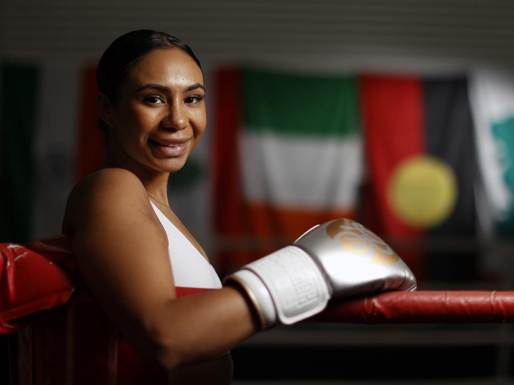 Young female boxer in ring, gloves raised, portrait