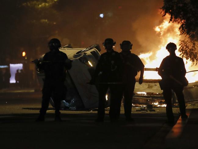 Police stand near a overturned vehicle and a fire as demonstrators protest the death of George Floyd near the White House in Washington. Picture: AP