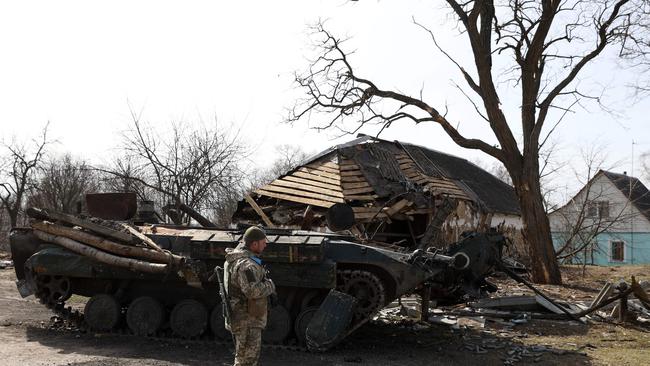 A Ukrainian soldier stands in front of a destroyed Russian armoured personnel carrier in a village on the frontline of the northern part of Kyiv region. Photo by Anatolii Stepanov / AFP