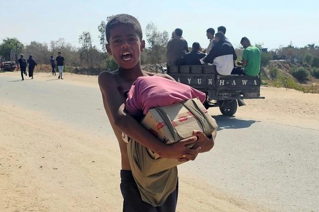 A boy walks with humanitarian aid relief packages as displaced Palestinians receive aid from a US-backed foundation in Rafah in southern Gaza