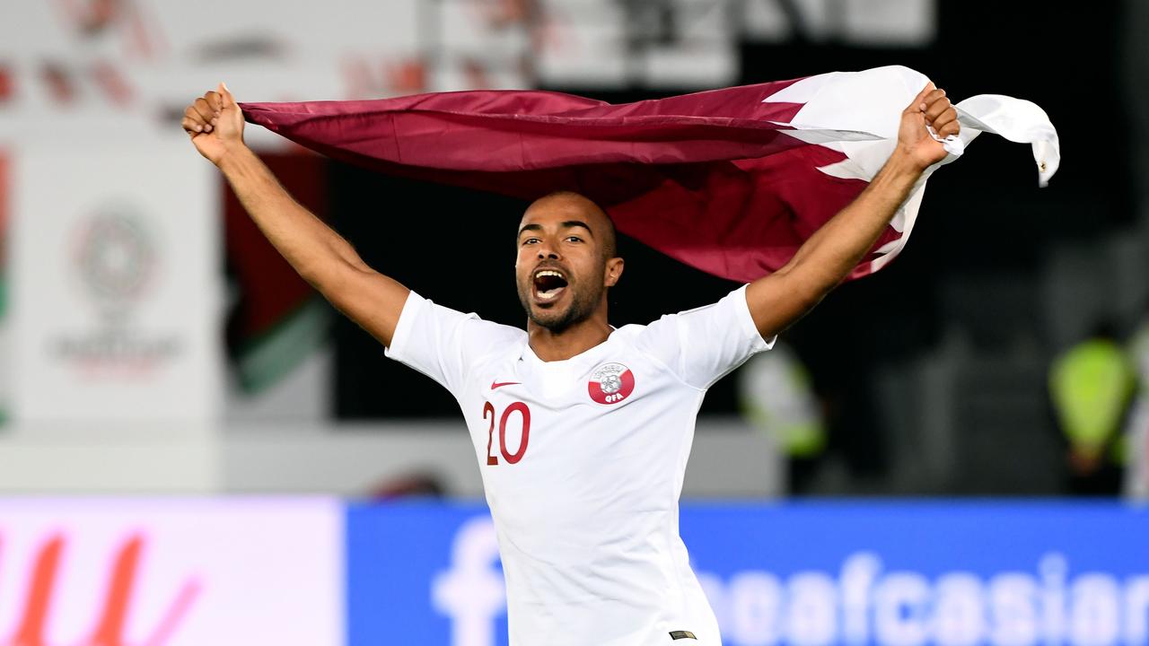 Qatar's midfielder Ali Yahya celebrates with the national flag after beating South Korea.