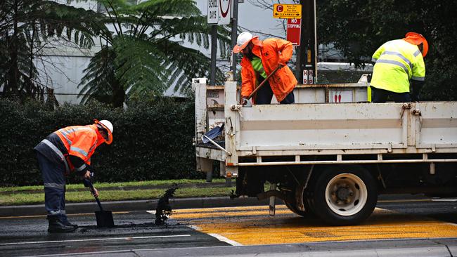 RMS crew fill up a large pothole on the M1 turn off at Wahroonga last week. Picture: Adam Yip