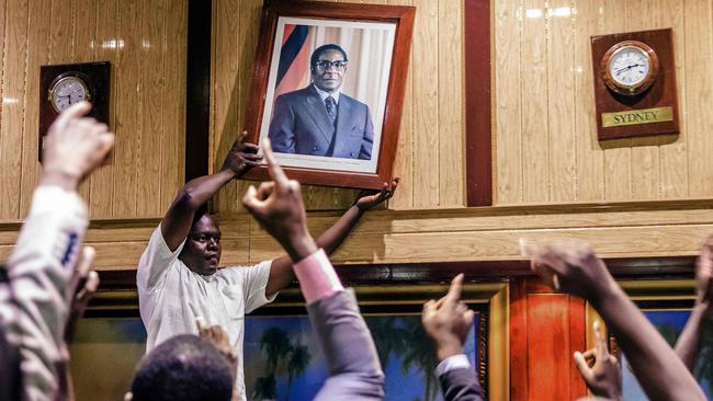 People remove the portrait of former Zimbabwean President Robert Mugabefrom from the wall at the International Conference centre, after his resignation. Picture Jekesai Njikizana/ AFP.