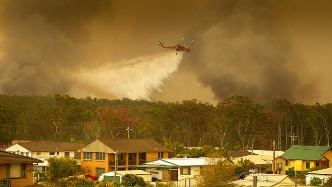 An Aircrane water bombing helicopter drops water on a bushfires in Harrington, north east of Sydney on Friday.