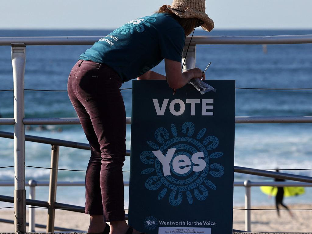 A volunteer hangs a banner outside a polling station on Bondi Beach in Sydney. Picture: AFP