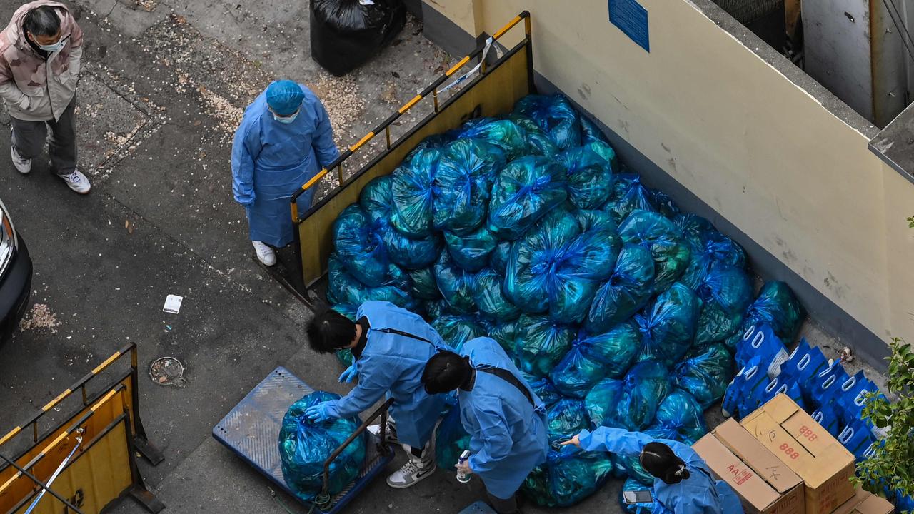 This photo taken on April 16 shows workers in protective gear sorting bags of vegetables to be delivered to residents of a neighbourhood. Picture: Hector Retamal/AFP