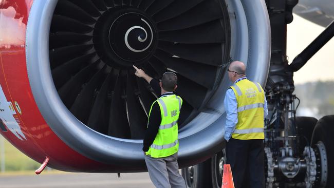 Safety Inspectors look over the engine of Air Asia flight D7207 at Brisbane Airport in Brisbane, Tuesday, July 4, 2017. An AirAsia flight from the Gold Coast was diverted to Brisbane after a bird strike allegedly caused loud bangs and sparks to come from an engine. Picture: AAP/Darren England