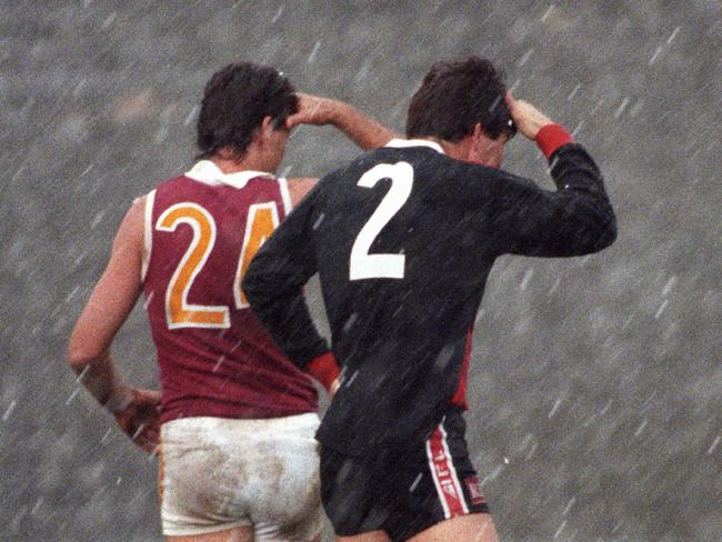 Roger Merrett (left) and Danny Frawley. shield their eyes from strong hail during a 1993 match between the Brisbane Bears and St. Kilda.