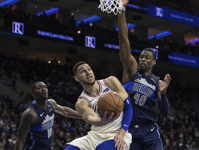 Philadelphia 76ers' Ben Simmons, center, shoots as he gets past Dallas Mavericks' Dorian Finney-Smith, left, and Harrison Barnes, right, during the second half of an NBA basketball game, Sunday, April 8, 2018, in Philadelphia. The 76ers won 109-97. (AP Photo/Chris Szagola)