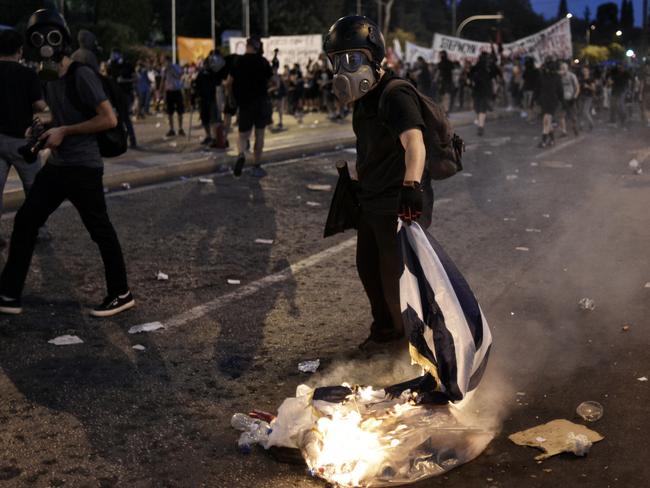 A protester burns a Greek flag.