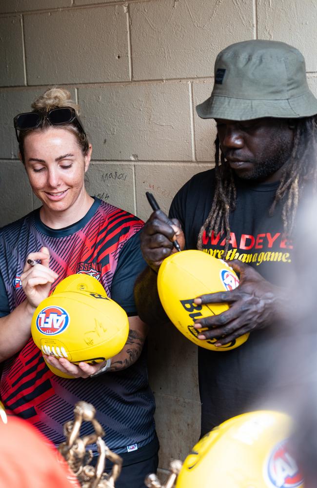 Lauren Taylor (Sturt) and Anthony McDonald-Tipungwuti (Essendon) sign for the fans in Wadeye. Picture: Supplied/John Ross.