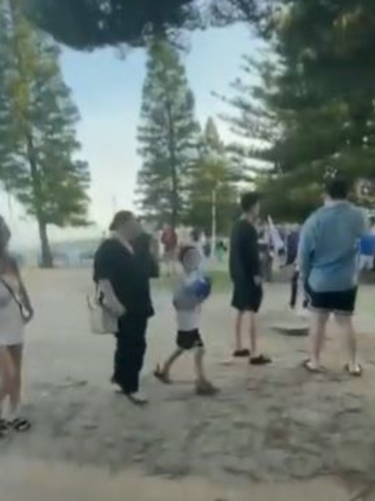 The woman and child walked past a group carrying Israeli flags at Coogee Beach. Picture: X