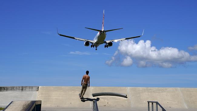 A skateboarder looks on from a skate park as a Virgin commercial aircraft from Sydney lands at the Gold Coast Airport. (AAP Image/Dave Hunt).