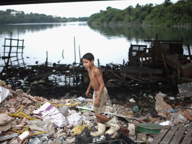 A boy looks for items to recycle along the polluted Cunha canal which flows into the notoriously polluted Guanabara Bay, site of sailing events for the Rio 2016 Olympic Games.