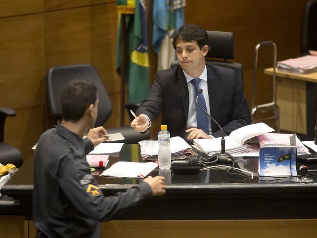 Brazilian judge Daniel Werneck Cota talks to a military police officer before the pre-trial hearing. Picture: AP