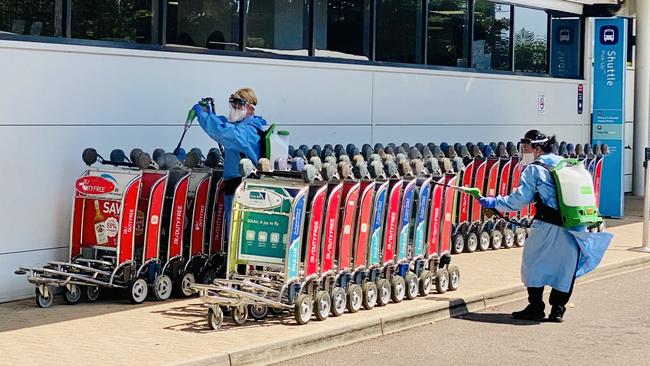 Darwin International Airport. Staff spray baggage trolleys dressed in full PPE as part of the airports Covid health plan. Picture: Gary Shipway