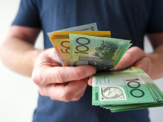 A man counting Australian dollar bills. A picture that describes buying, paying, handing out money, or showing money. Australian cash money generic