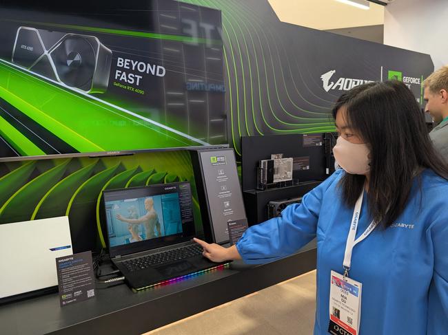 Mia Qu of Gigabyte gestures to a gaming laptop enhanced with a superfast Nvidia chip as AI capabilities head for personal computers during the Consumer Electronics Show (CES) in Las Vegas, Nevada on January 9, 2025. Artificial intelligence is moving from data centers to âthe edgeâ as computer makers flocking to CES build the technology into laptops, robots, cars and more devices closer to home. (Photo by Glenn CHAPMAN / AFP)