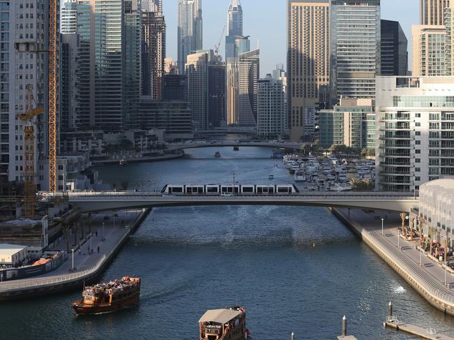 In this April 1, 2015 photo, tourists and visitors enjoy their dhow cruise trips at the Marina water canal as a tram crosses on a bridge in Dubai, United Arab Emirates. Dubai Marina is finally coming into its own after years of seemingly endless construction work. Hewn out of the desert and connected to the Persian Gulf by channels at each end, the 3.5 kilometer (2.2 mile) U-shaped canal would be an engineering marvel even without its skyline. (AP Photo/Kamran Jebreili)