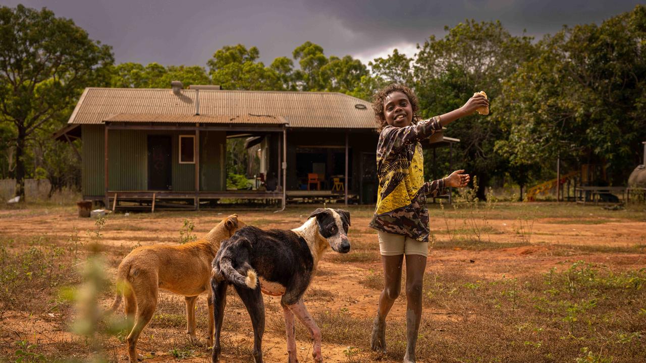 Anastias Pascoe entertains camp dogs outside Gamardi.