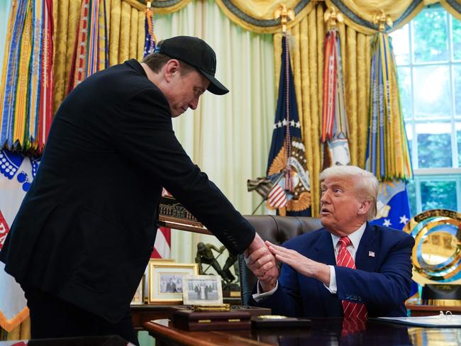 (FILES) US President Donald Trump shakes hands with Elon Musk after Trump gifted him with a 