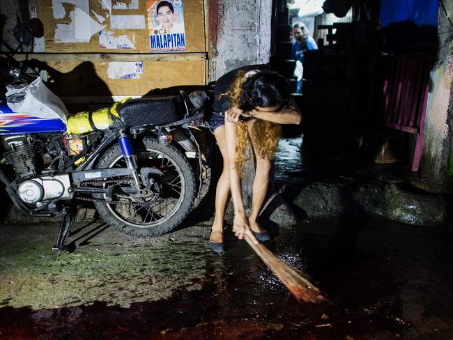 A relative cries as she sweeps the blood of a relative gunned down by an unidentified killer in Manila. There have been more than 3600 victims of the president’s crackdown. Picture: Noel Celis/AFP Photo