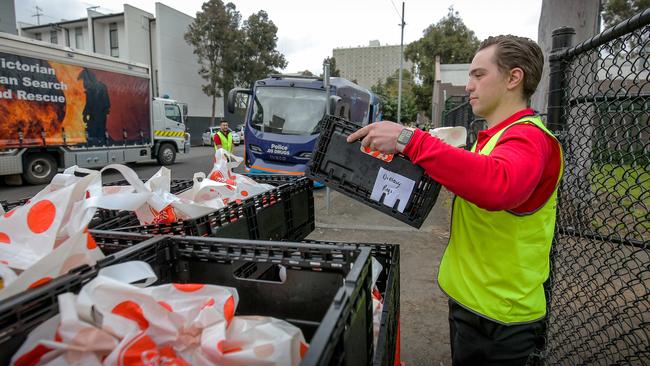 A Coles worker deliveries grocery boxes to residents. Picture: Martin Keep