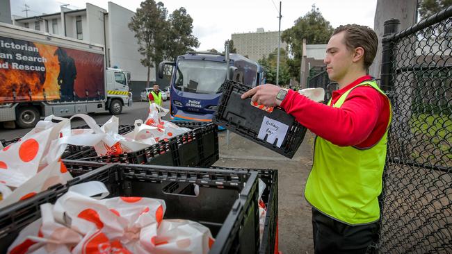 A Coles worker deliveries grocery boxes to residents. Picture: Martin Keep