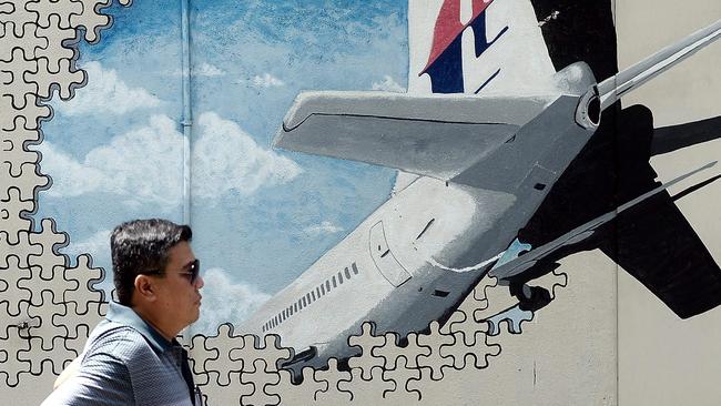 (FILES) This file photo taken on March 8, 2016 shows a Malaysian man walking in front of a mural of missing Malaysia Airlines MH370 plane in a back-alley in Shah Alam. The disappearance of the Boeing 777 carrying 239 passengers and crew almost four years ago is one of aviation's greatest mysteries, with an Australian-led hunt across a 120,000 square-kilometre (46,000 square-mile) zone failing to reveal the crash site.  / AFP PHOTO / Manan VATSYAYANA / TO GO WITH Australia-Malaysia-China-aviation-MH370,FOCUS by Glenda Kwek