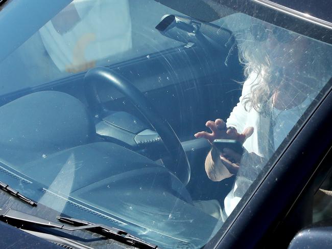 A person in the drivers seat of their car on their phone while at a set of traffic lights, Warringa Road, Frenchs Forest, Sydney. 24th September, 2019. Picture by Damian Shaw