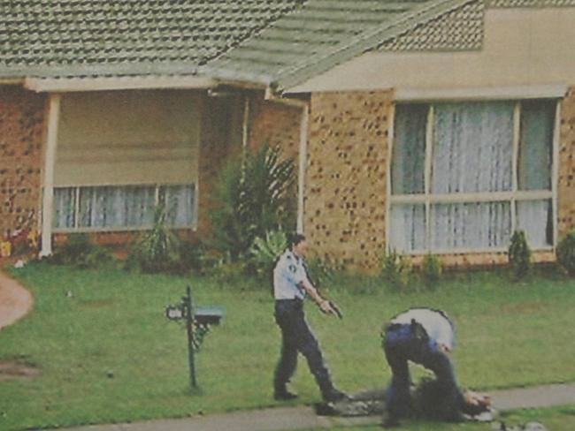 Police keep a gun trained on Omar Baladjam while a colleague checks his condition after police shot him on Wilson Road in Green Valley, southwestern Sydney, when he opened fire on them during a counter-terrorism raid.