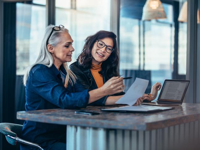 CAREERS: Performance reviews are becoming more frequent so feedback can be provided while it is still relevant. Picture: iStockTwo women analyzing documents while sitting on a table in office. Woman executives at work in office discussing some paperwork.