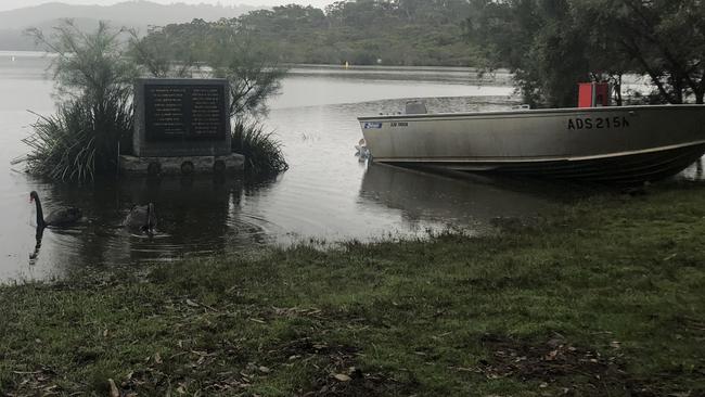 Swims swim around a war memorial plaque at the Manly Dam reservoir at Manly Vale that was surrounded by high floodwaters on Monday. Picture: Jim O'Rourke