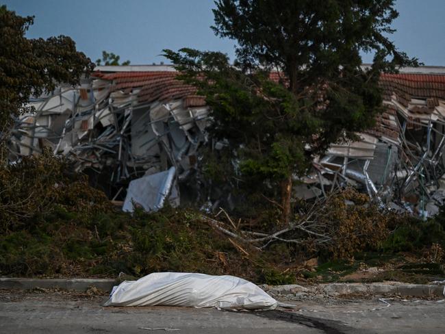 The body of a Hamas militant in a body bag is left on the street near a home at the kibbutz where dozens of civilians were killed days earlier by Hamas militants near the border.