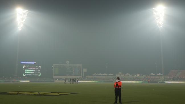 A security guard covers his face from smoke haze during the Big Bash League match. Picture: Getty Images