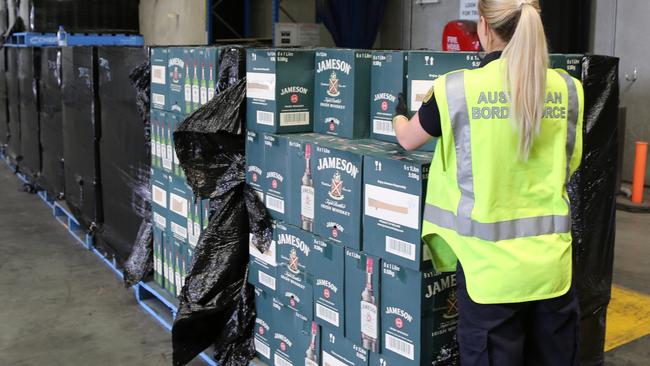 A border force official moves pallets of seized alcohol.