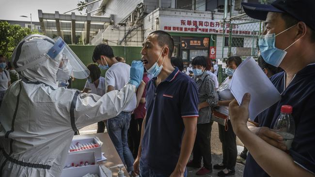 A Chinese epidemic control worker tests for COVID-19 on a man who has had contact with the Xinfadi market in Beijing. Picture: Getty Images