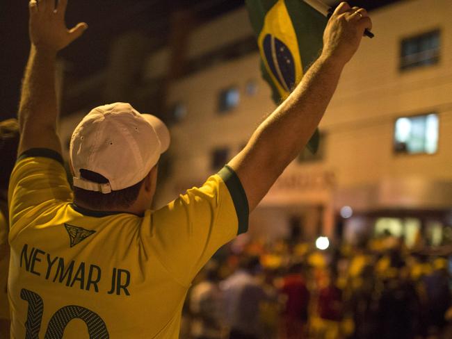 A Brazil soccer fan wearing a Neymar jersey waves a Brazilian flag outside Sao Carlos Hospital where Brazil's soccer player Neymar was taken after being injured during the World Cup quarterfinal soccer match against Colombia in Fortaleza, Brazil, Friday, July 4, 2014. Brazil's team doctor says Neymar will miss the rest of the World Cup after breaking a vertebrae during the team's quarterfinal win over Colombia. (AP Photo/Renata Brito)