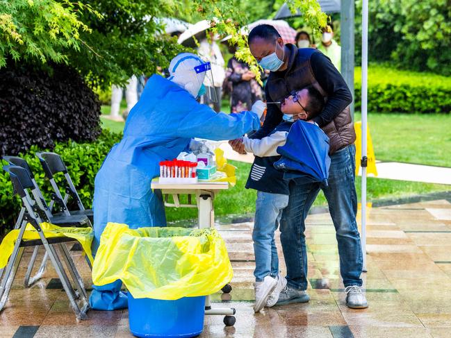 A health worker takes a swab sample from a child to be tested for Covid-19 in a compound under lockdown in the Pudong district in Shanghai. Picture: AFP / China OUT