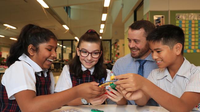 28/4/22: Daniel Langford Head of School of Curiosity at St John XXIII Catholic College with year 6 students, from left, Denika Fernandopulle, Mia Lucas and Rafael Nicodemu. Picture: John Feder