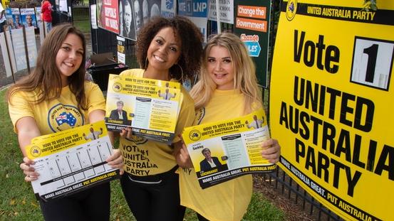 Backpackers Mira Sutton (UK), Ali Cofta (Brazil), and Katie May (UK) handing out Clive Palmer’s United Australia Party how to vote cards at the Parramatta State School in Cairns. Picture: Brian Cassey