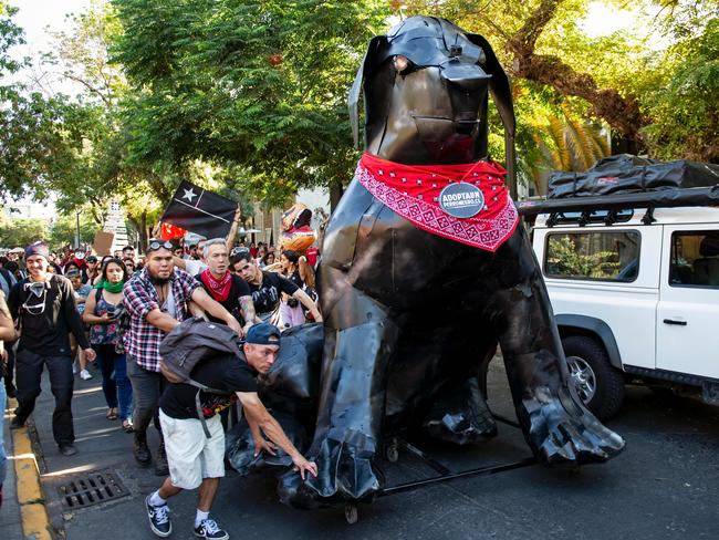 Protesters in Santiago carry a metal sculpture of the so-called Negro Matapacos dog. Picture: AFP