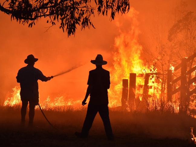 Residents defend a property from a bushfire at Hillsville near Taree, 350km north of Sydney. Picture: PETER PARKS / AFP