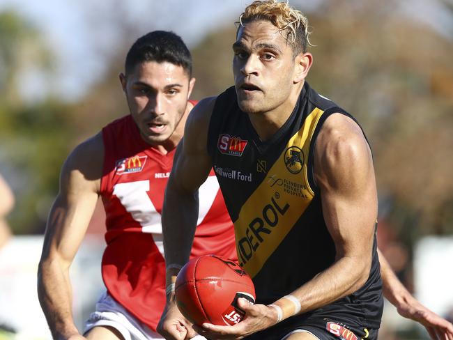 Glenelg’s Dom Barry handballs against North Adelaide’s Lee Minervini. Picture: SARAH REED