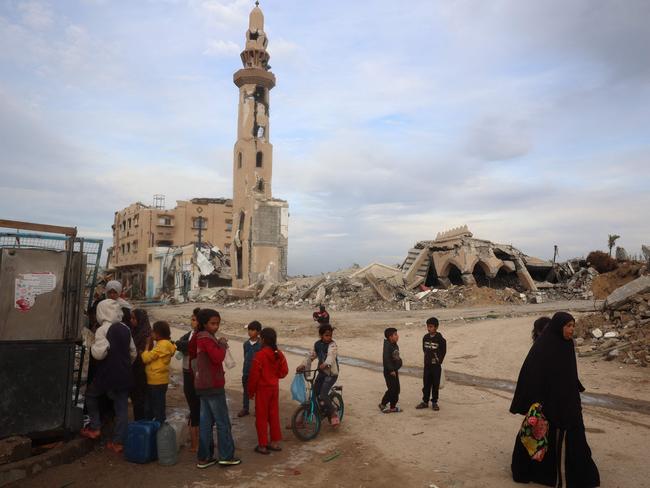 Palestinians refill on water next to a destroyed mosque at the Nuseirat refugee camp in the central Gaza Strip on March 3, 2025, during the holy Muslim fasting month of Ramadan. (Photo by Eyad BABA / AFP)