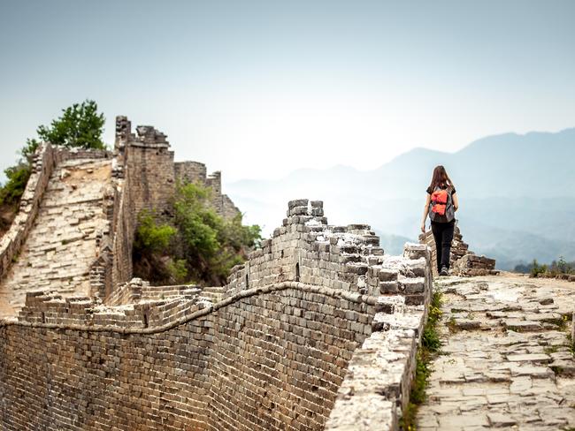 Solo Woman Tourist at walking on the Great Wall Of China. She is wearing a backpack.